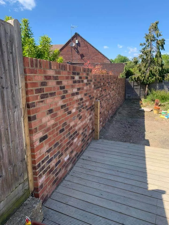 A brick wall next to a wooden deck.