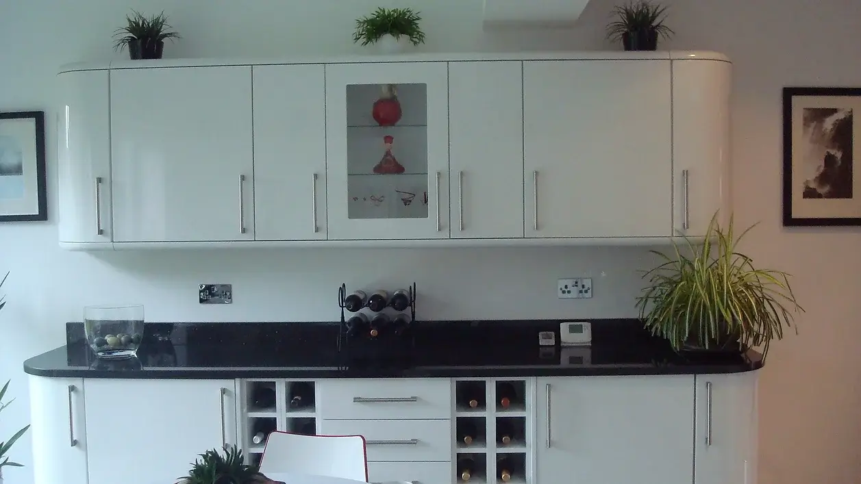 A kitchen with white cabinets and black counter tops.